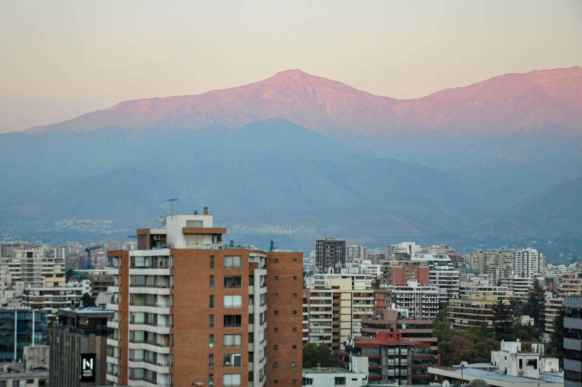 Edificios de Santiago al atardecer, con la cordillera teñida de rosa al fondo.